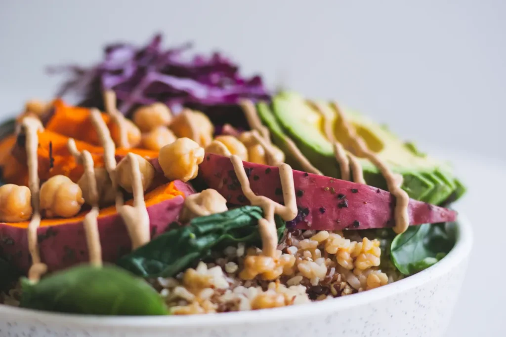 A colorful Buddha bowl with grains, roasted vegetables, avocado, and a creamy tahini dressing.