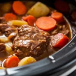 Rich beef stew simmering in a pot with vegetables and herbs