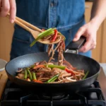 Stir-frying vegetables and meat in a wok on high heat